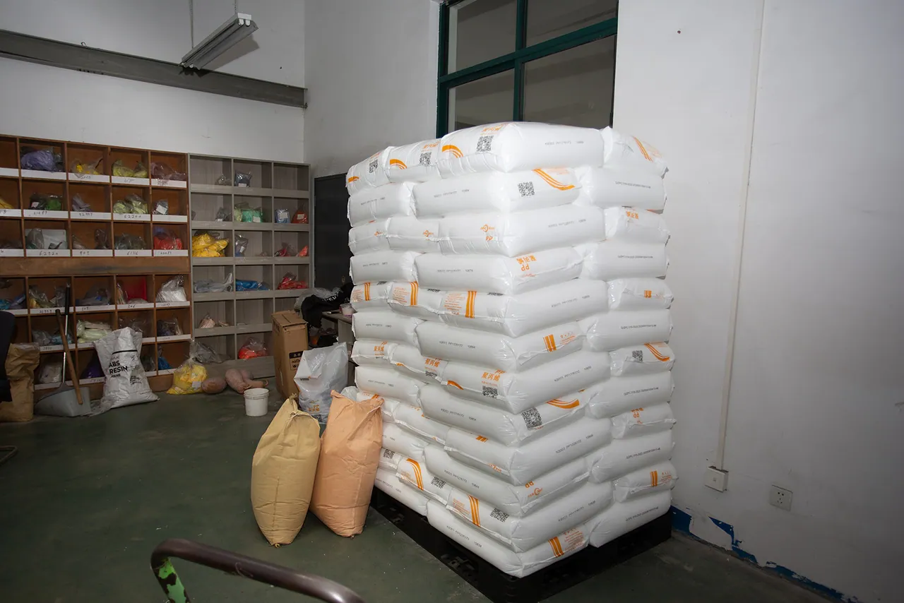 Bags of raw polyester granules stacked on pallets in the raw material store