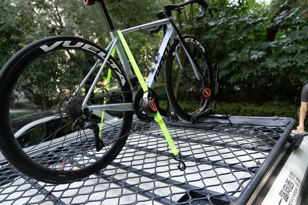 Auto-retract tie-down reel securing a bicycle to a truck bed cargo net