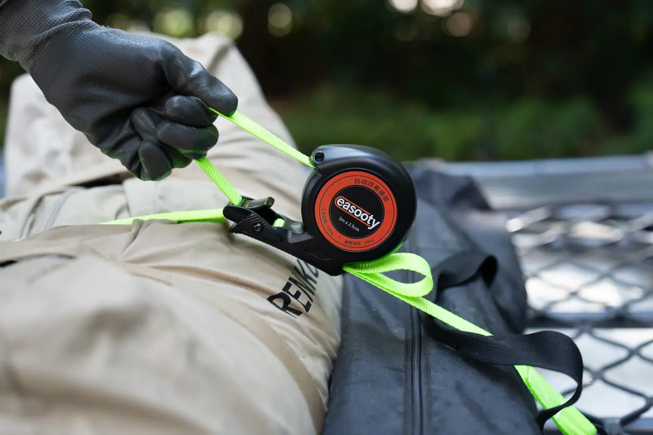 Auto-retract tie-down reel fastening a bag to a truck bed cargo net