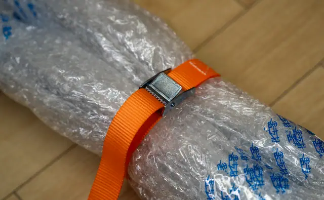 Cam buckle strap cinched around a bubble-wrapped package